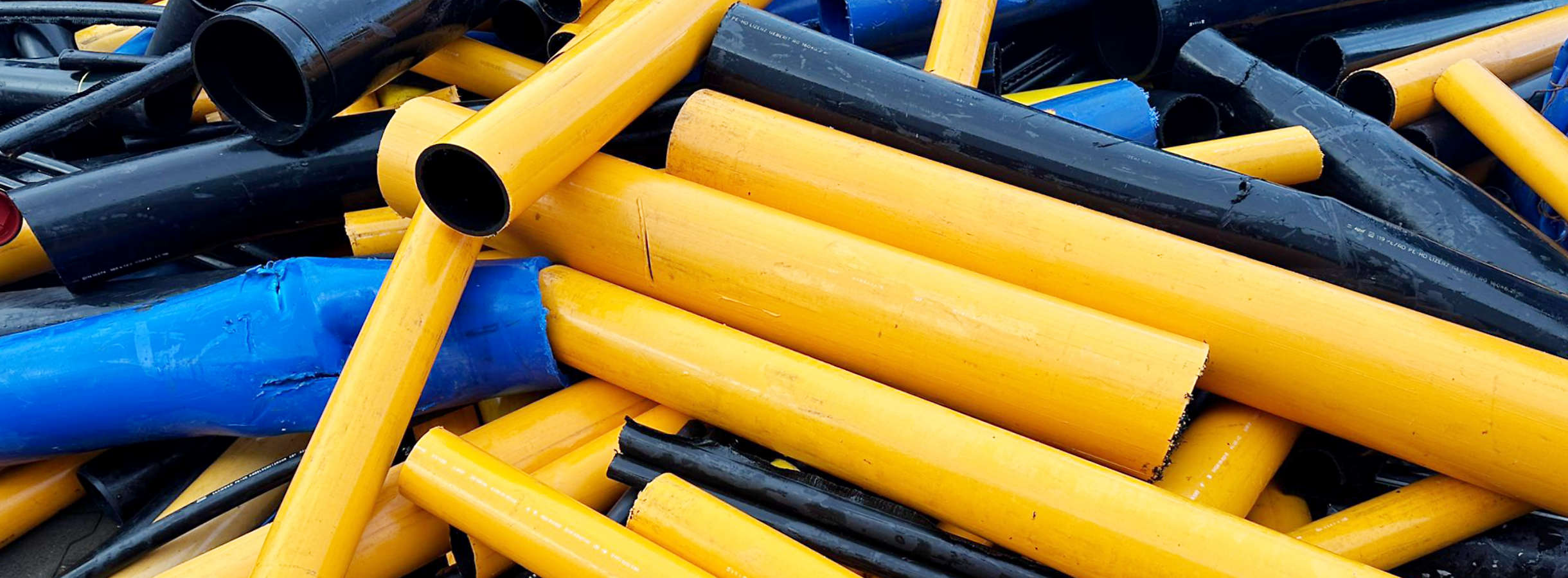 Kaputte gelbe, blaue, schwarze Kunststoffrohre aus Bauresten und aus Rückbau alter Rohrsysteme liegen durcheinander zu einem Kunststoff-Haufen gestapelt. Die Ansammlung von Kunststoffrohren liegt auf dem Gelände der Xpress Plastics Außenstelle in Hamburg.