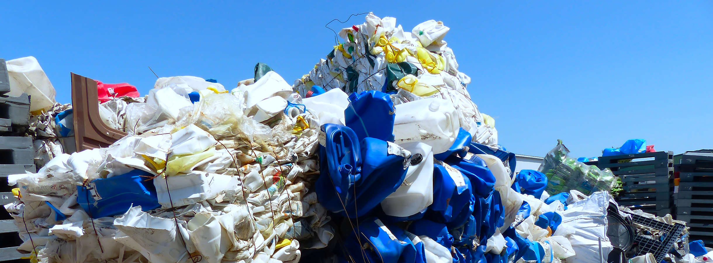 Ansammlung von entsorgten Kunststoffen wie bunten, weißen Kanistern, unterschiedlicher Kunststoffpaletten, Plastik-Rohren, Abfalltonnen, Plastikeimer & Kunststofffässer wartet auf Aufbereitung auf dem Gelände des Recyclings-Unternehmens Xpress Plastics.